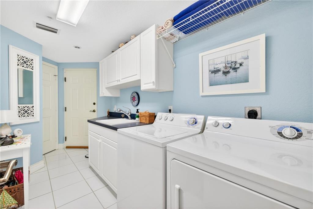 Washroom with light tile patterned floors, cabinet space, and washing machine and clothes dryer