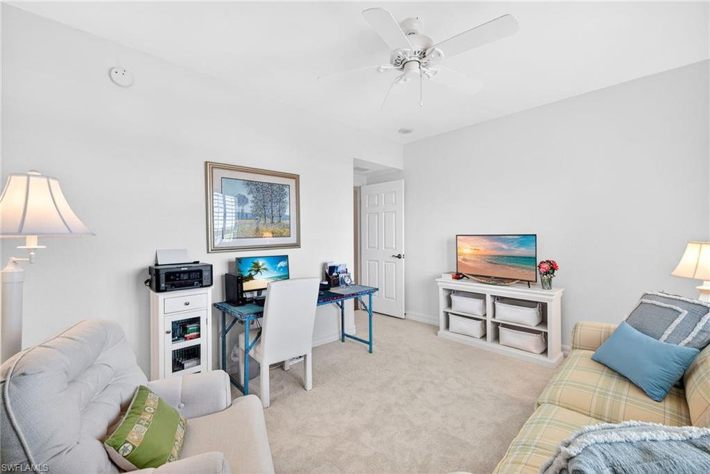Carpeted home office featuring a ceiling fan