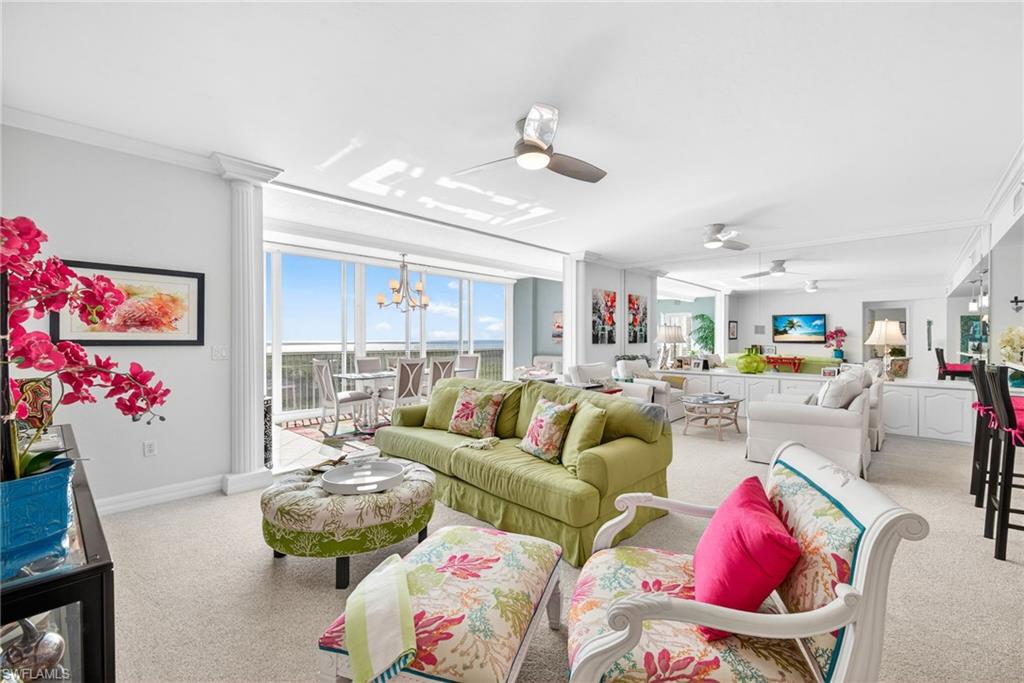 Living room featuring crown molding, ceiling fan, light colored carpet, a chandelier, and ornate columns