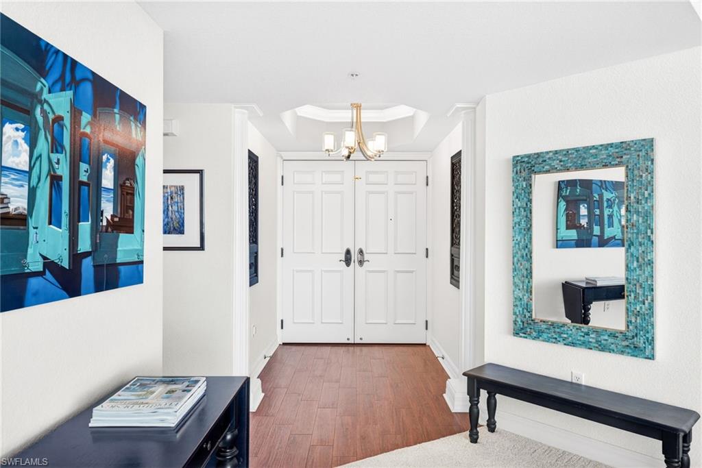 Entryway featuring wood finished floors, a chandelier, and a tray ceiling
