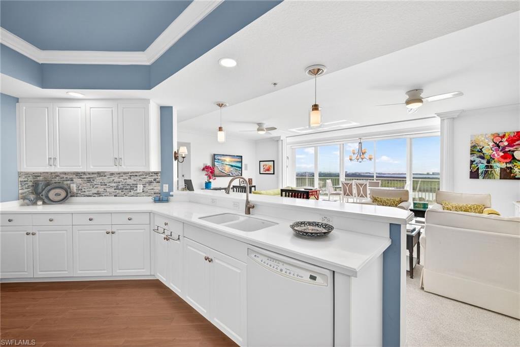 Kitchen featuring a chandelier, crown molding, dishwasher, white cabinetry, and a peninsula