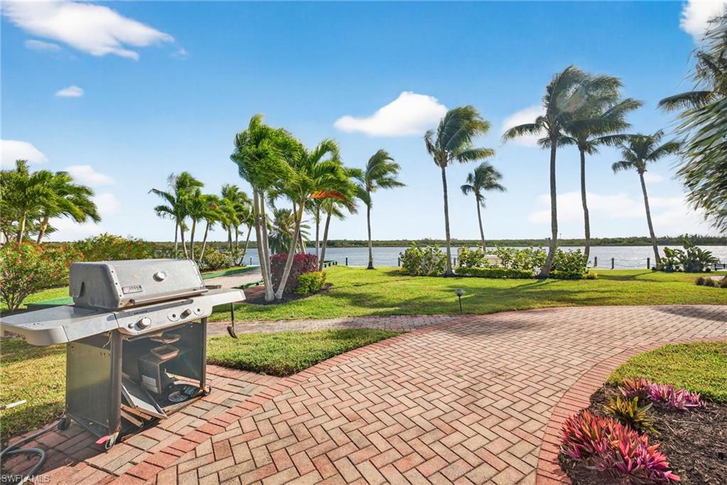 View of patio with area for grilling and a water view