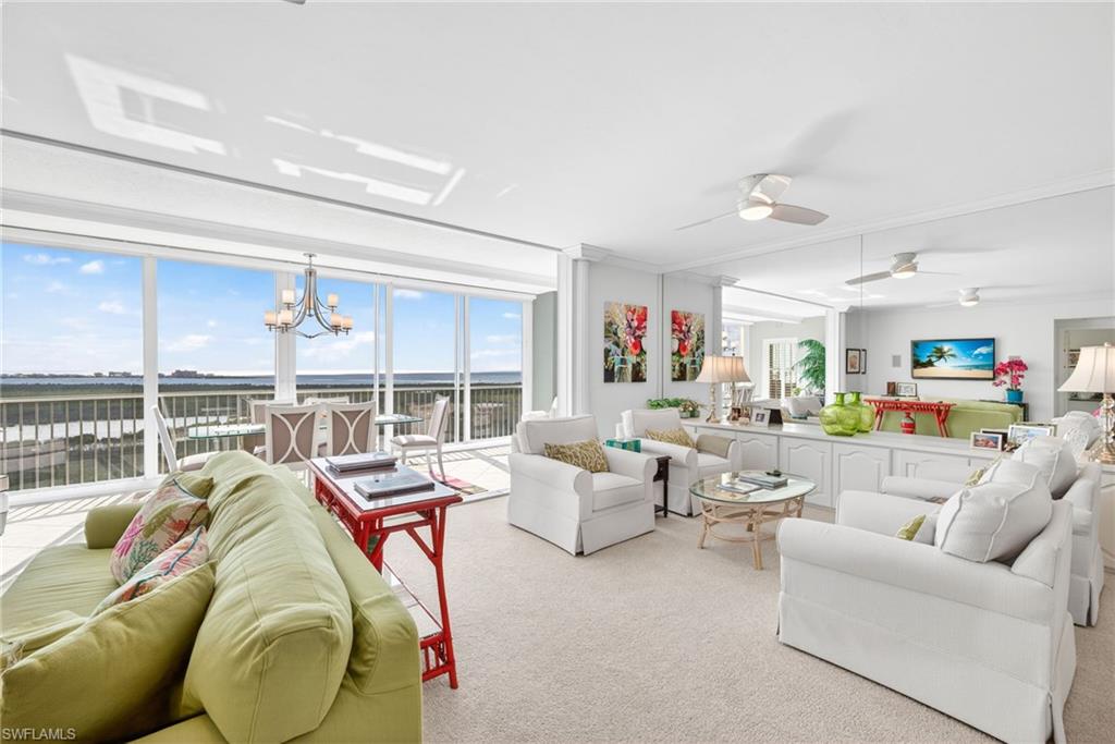 Carpeted living area with plenty of natural light, a chandelier, and ceiling fan