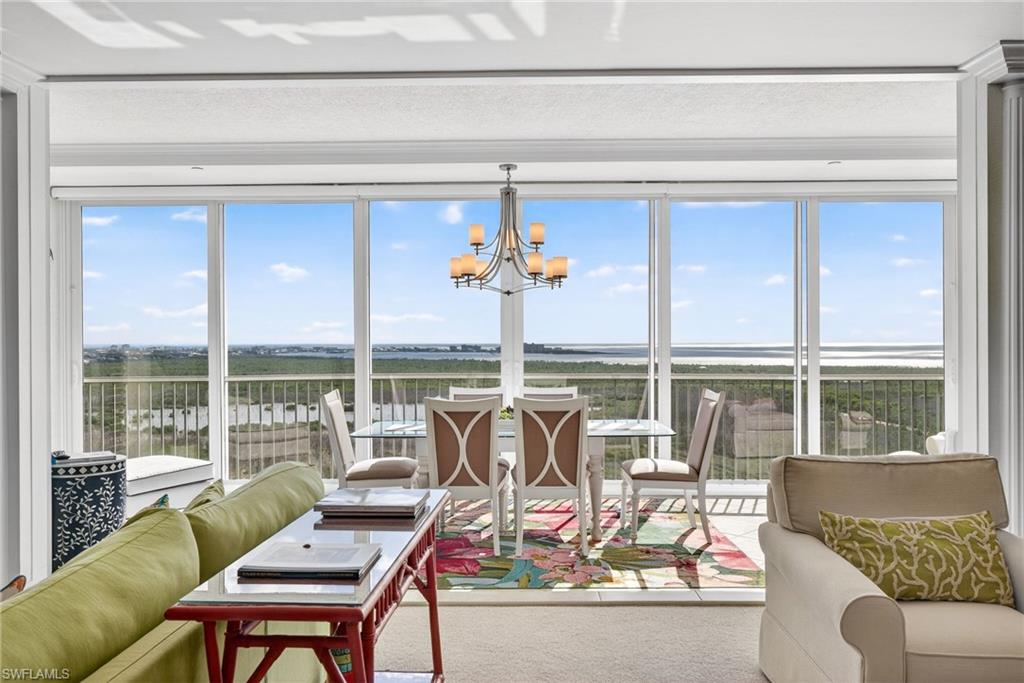 Sunroom with a chandelier, plenty of natural light, a water view, and carpet flooring