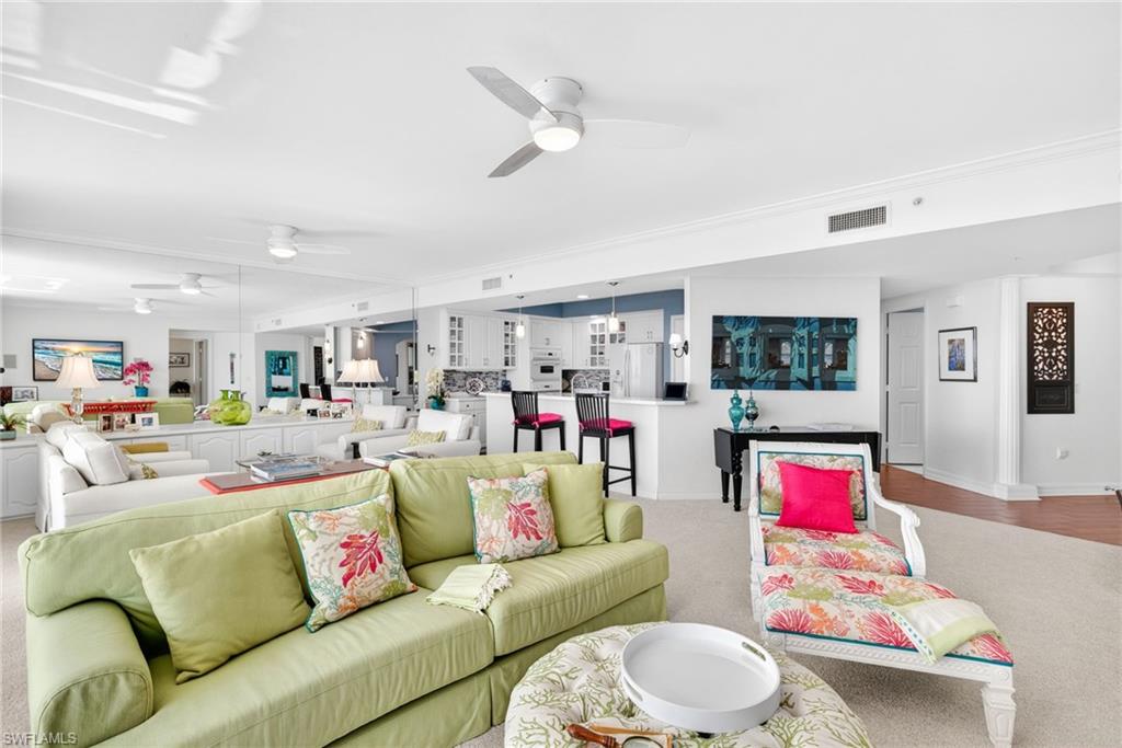 Carpeted living room featuring ceiling fan and baseboards