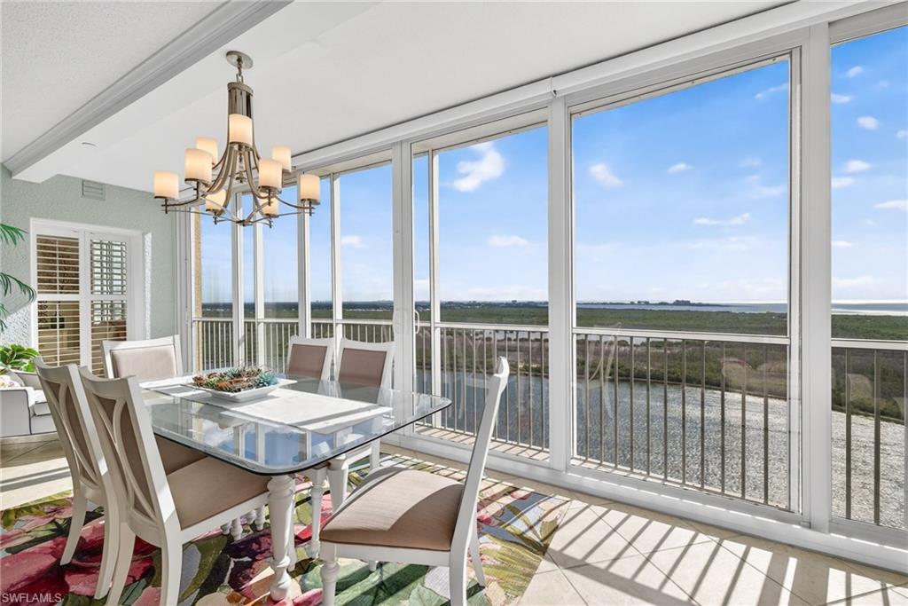 Sunroom featuring a water view, a chandelier, and beam ceiling