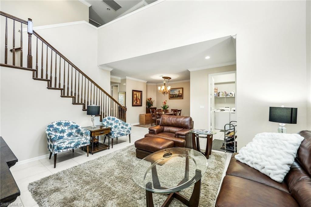 Living area featuring crown molding, stairway, separate washer and dryer, a chandelier, and light tile patterned flooring