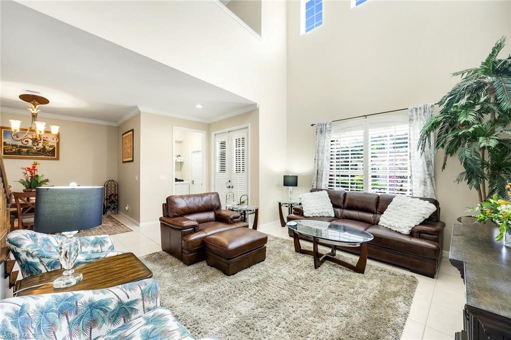 Living area with light tile patterned floors, crown molding, and a chandelier