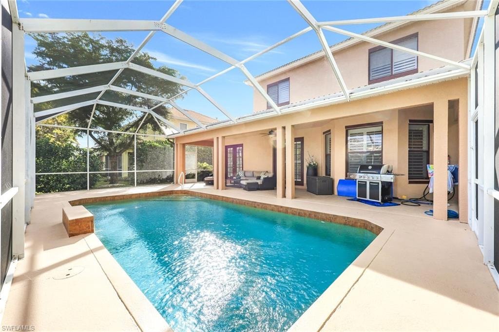 Swimming pool featuring a sunroom, outdoor lounge area, a patio area, area for grilling, and glass enclosure