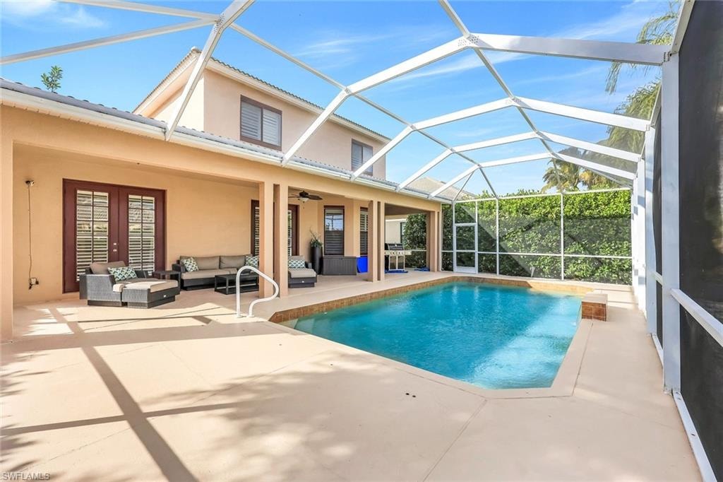 Swimming pool with a sunroom, an outdoor hangout area, a patio, glass enclosure, and french doors