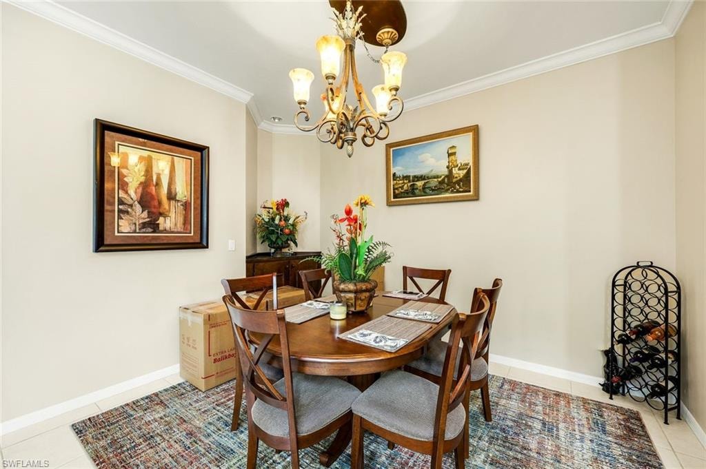 Dining area featuring light tile patterned floors, ornamental molding, and a chandelier