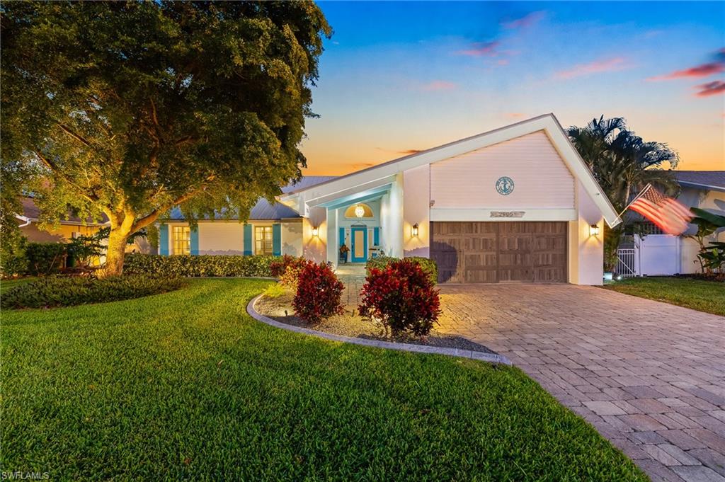 View of front facade featuring decorative driveway, a front yard, stucco siding, and a garage
