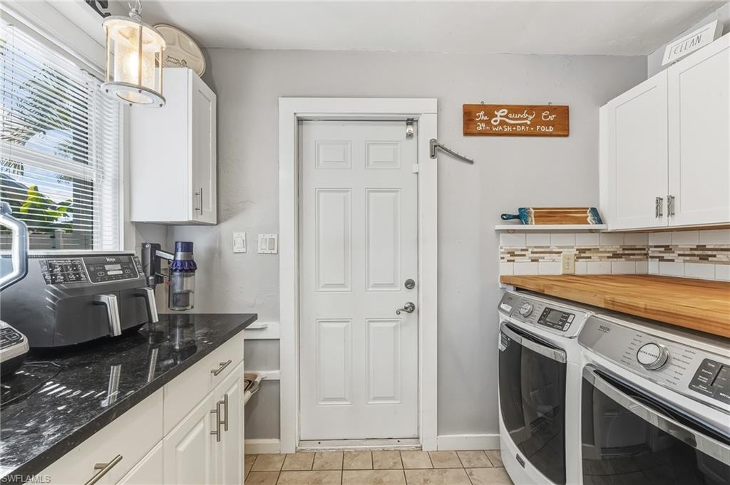 Kitchen featuring white cabinets, pendant lighting, washing machine and dryer, and backsplash