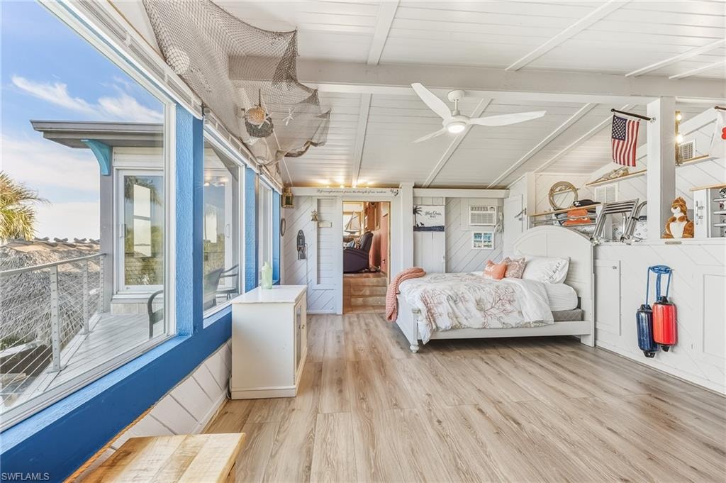 Bedroom with light wood-style floors, beam ceiling, ceiling fan, and wood walls