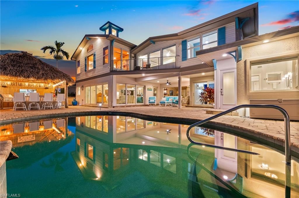 Rear view of house featuring a patio area, a balcony, an outdoor pool, and outdoor dining space