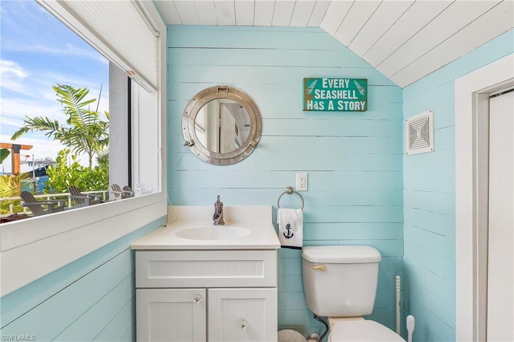 Bathroom with wood walls, vanity, and vaulted ceiling