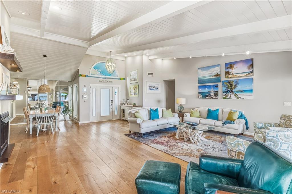 Living area with hardwood / wood-style floors, a towering ceiling, a chandelier, track lighting, and a fireplace
