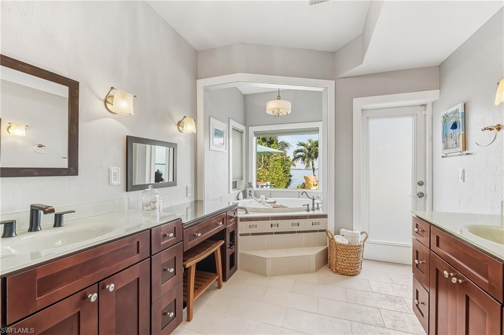 Full bathroom with a garden tub, two vanities, and light tile patterned floors