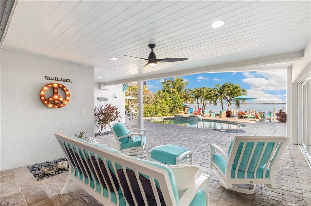 View of patio / terrace with a ceiling fan and a pool with connected hot tub