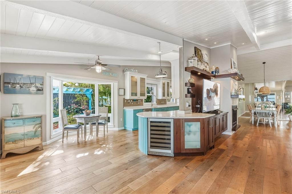 Kitchen with glass insert cabinets, decorative light fixtures, beverage cooler, wooden ceiling, and white cabinets