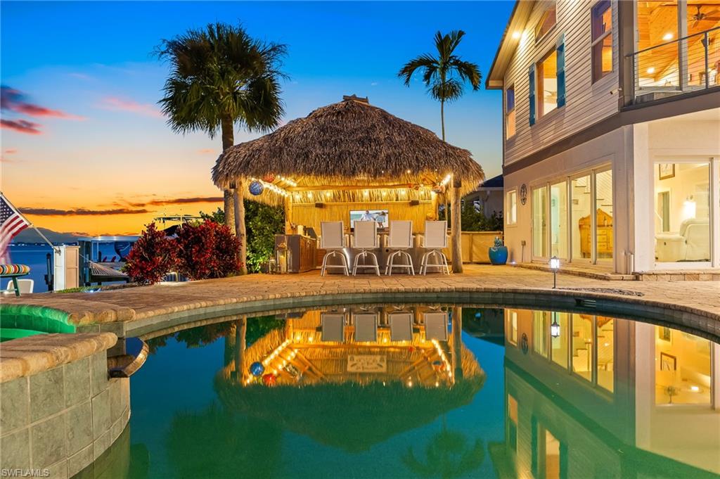 Pool at dusk featuring a patio area, a gazebo, and a pool with connected hot tub