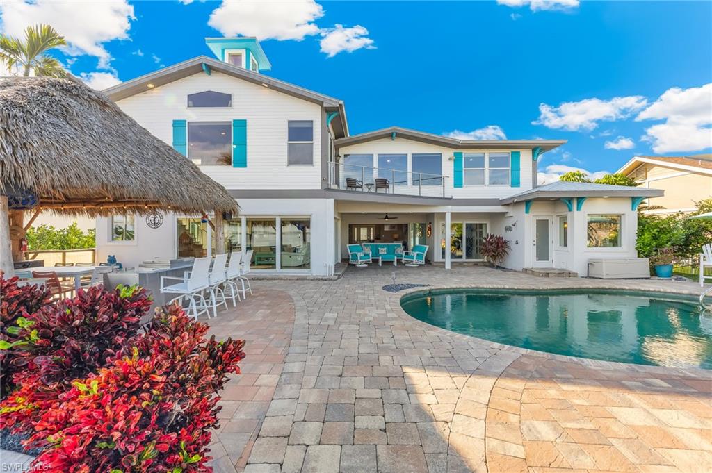 Back of property with a patio area, a balcony, outdoor lounge area, an outdoor pool, and ceiling fan