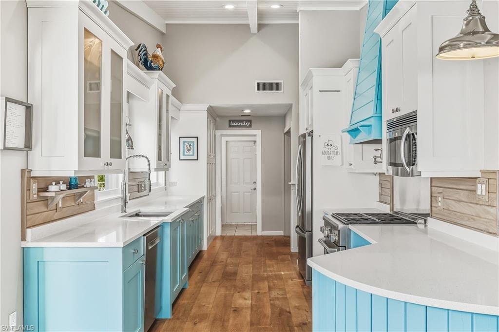 Kitchen featuring white cabinetry, blue cabinetry, light stone countertops, a high ceiling, and recessed lighting