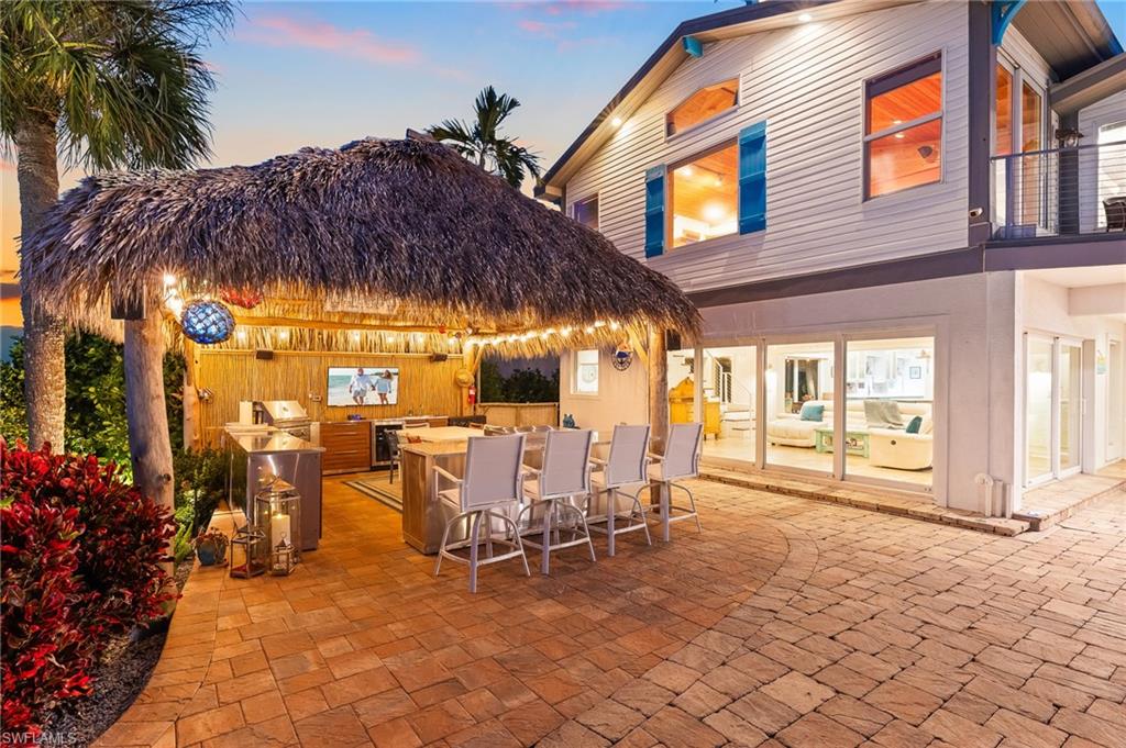 Patio terrace at dusk with a patio area, wine cooler, a balcony, and area for grilling