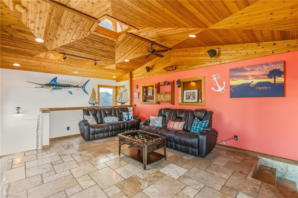 Living area with a skylight, wood ceiling, recessed lighting, stone tile floors, and ceiling fan