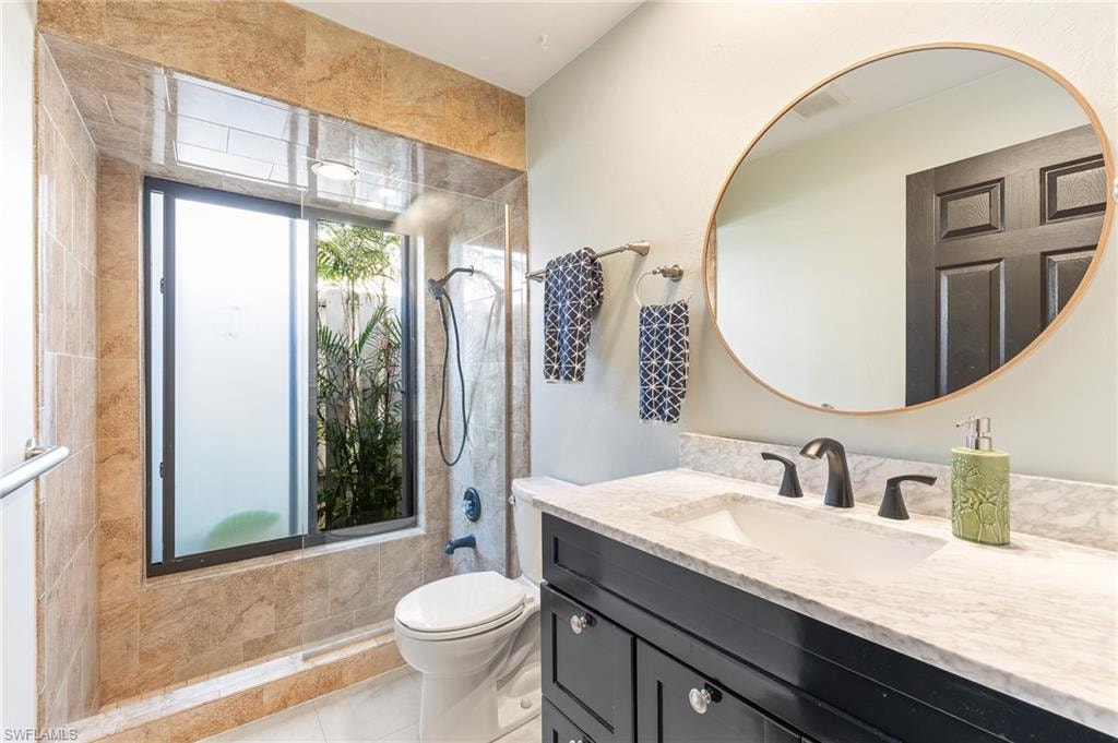 Full bath with vanity, tiled shower, and light tile patterned floors