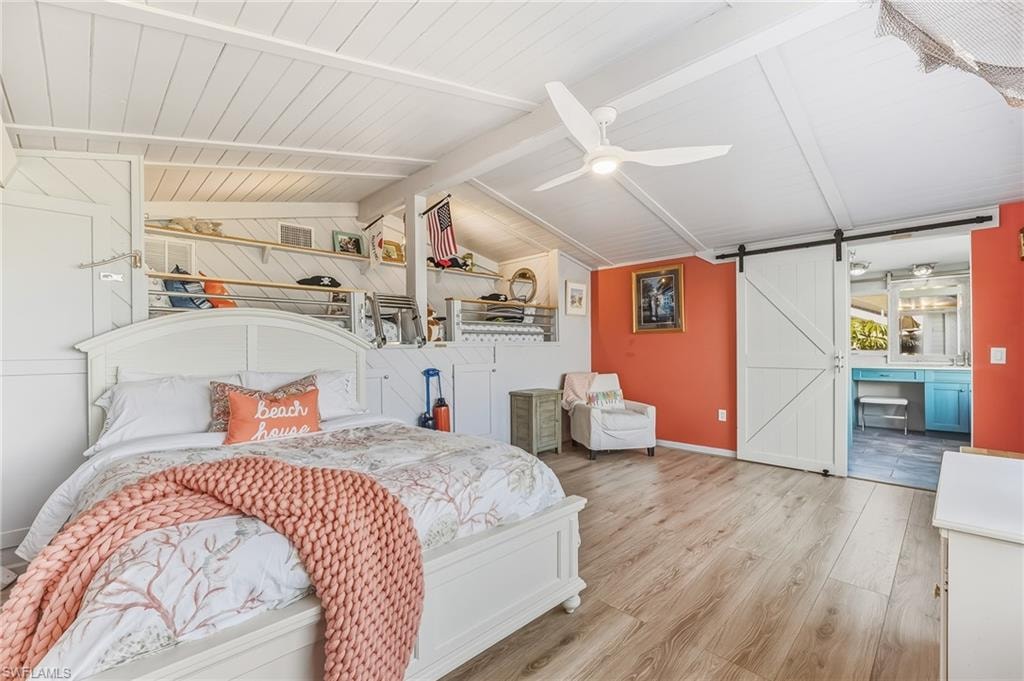 Bedroom with a barn door, wood finished floors, ceiling fan, and wood ceiling
