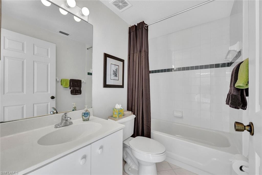 Bathroom with vanity, shower / bath combo, and light tile patterned flooring
