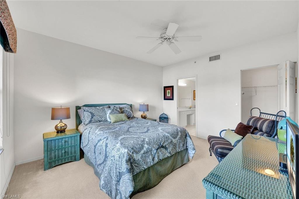 Main bedroom featuring a queen sized bed, carpet floors, ceiling fan, a large walk in closet, and ensuite bathroom
