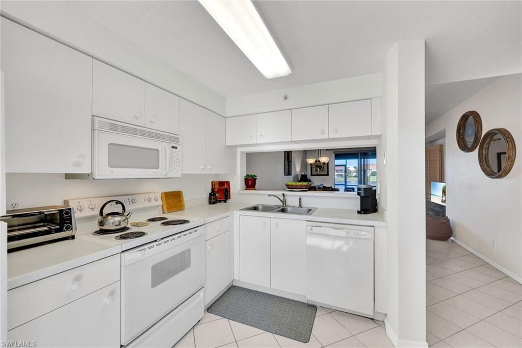 Kitchen featuring white appliances, light countertops, white cabinetry, and light tile patterned flooring