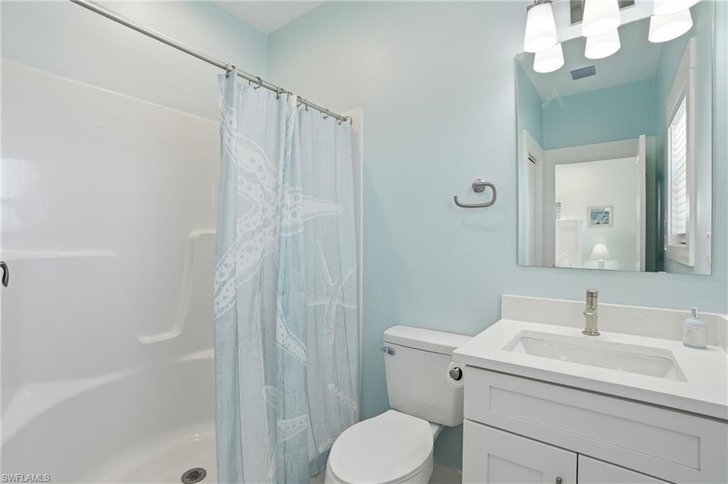 Full bathroom featuring a white vanity with an integrated sink, a sleek mirror, and a shower-tub combination with a white surround - Virtually Edited Image