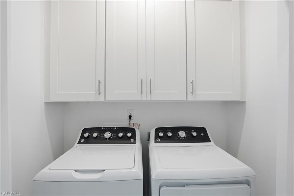 Dedicated laundry space featuring upper white cabinetry with brushed nickel hardware - Virtually Edited Image