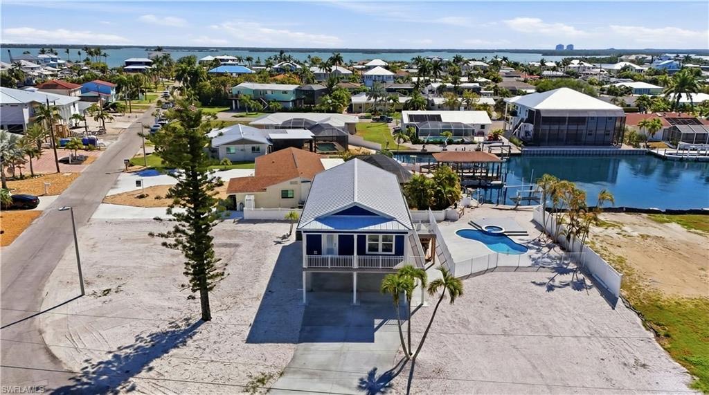 Elevated coastal residence featuring a metal roof, front balcony, and a private swimming pool with an integrated sparkling spa - Virtually Edited Image