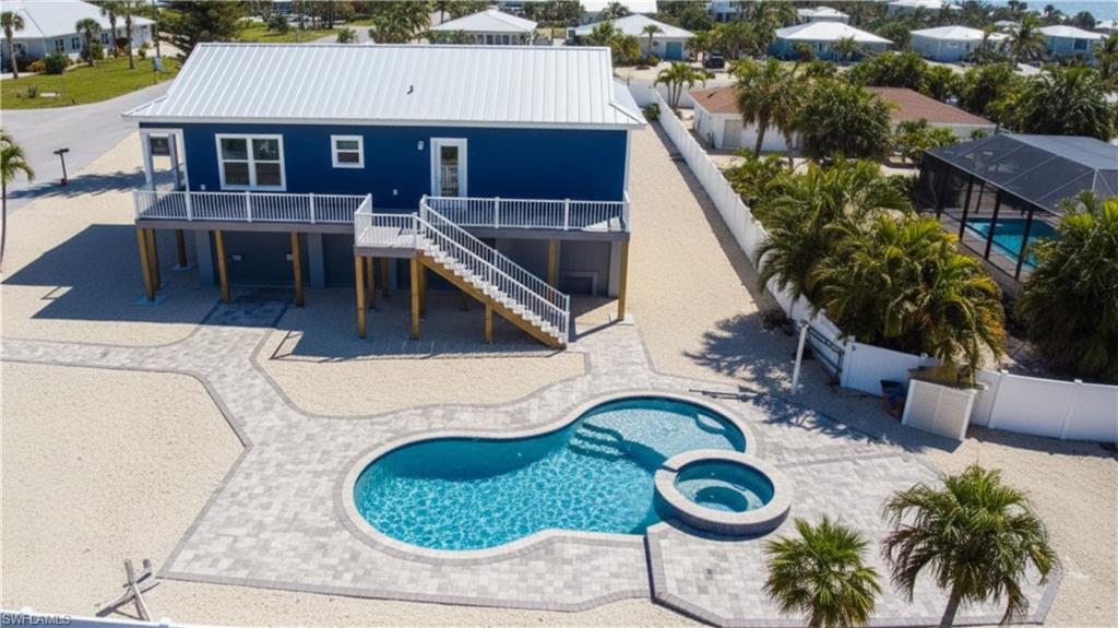 Rear view of property with a patio area, a metal roof, a pool with connected hot tub, a deck, and a residential view - -VIRTUALLY EDITED