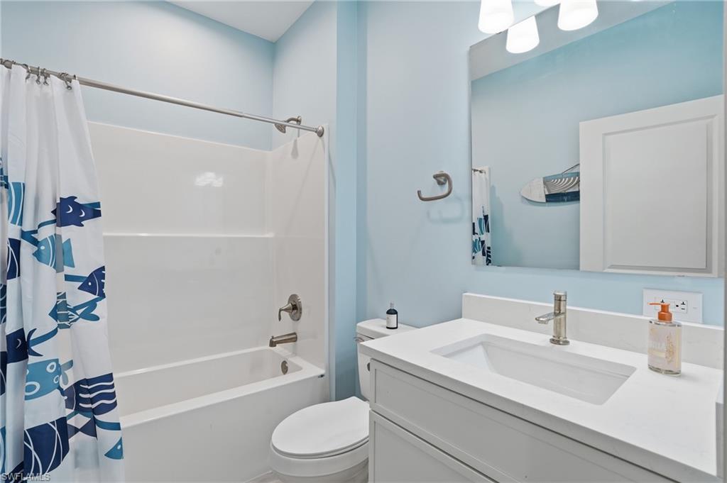 Full bathroom featuring a white vanity with integrated sink, brushed nickel faucet, and a wall-mounted mirror - Virtually Edited Image