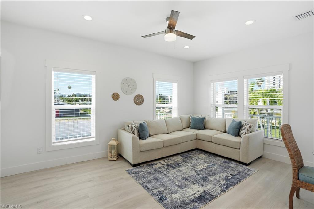 Bright interior space featuring light wood-finish flooring, recessed lighting, and a ceiling fan with light fixture - Virtually Edited Image