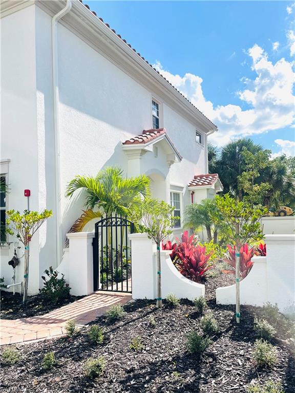 View of property exterior with a gate, stucco siding, and a tile roof