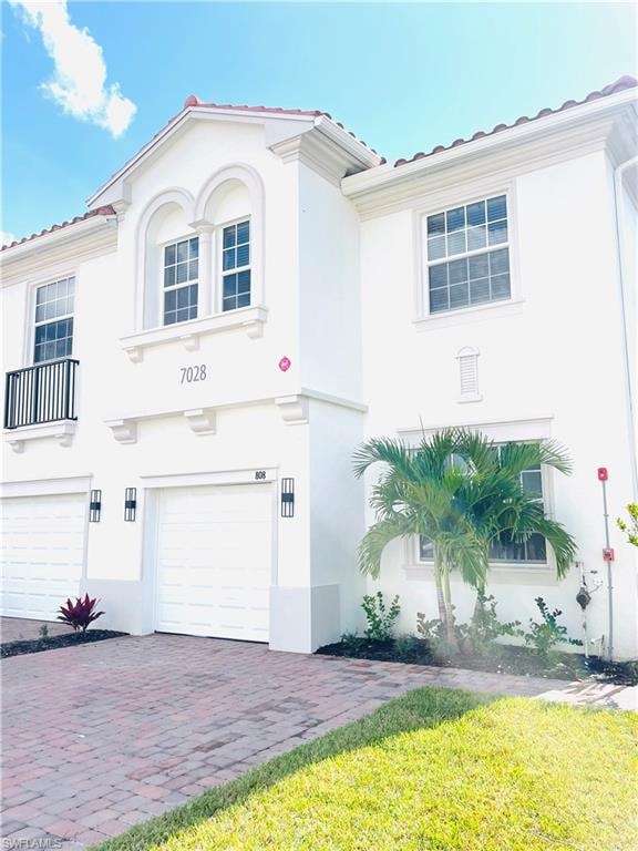 Mediterranean / spanish-style house with an attached garage, stucco siding, and a tiled roof