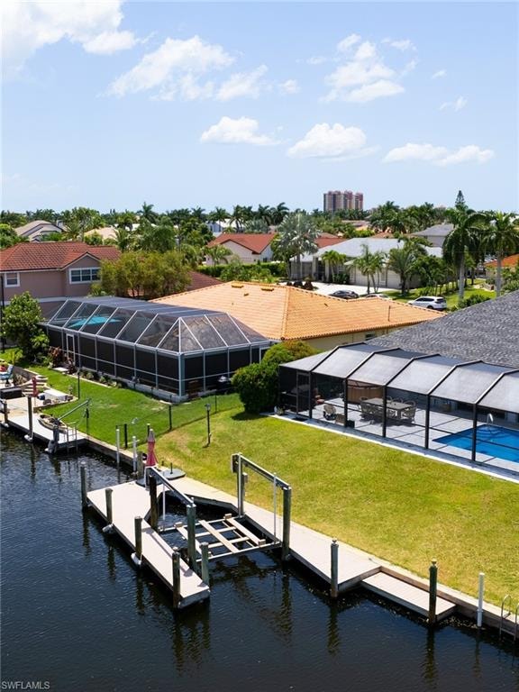 Dock with glass enclosure, a yard, a water view, boat lift, and a sunroom