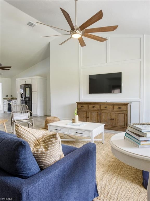 Living area featuring lofted ceiling, ceiling fan, wine cooler, and light colored carpet