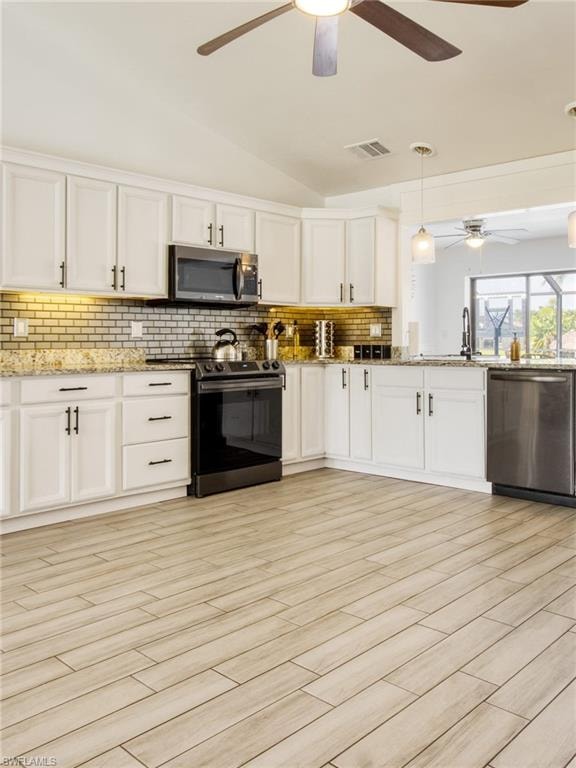 Kitchen featuring lofted ceiling, decorative light fixtures, stainless steel appliances, white cabinets, and tasteful backsplash