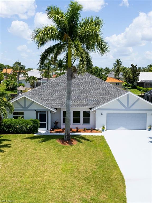 Ranch-style home with stucco siding, roof with shingles, concrete driveway, and a front yard