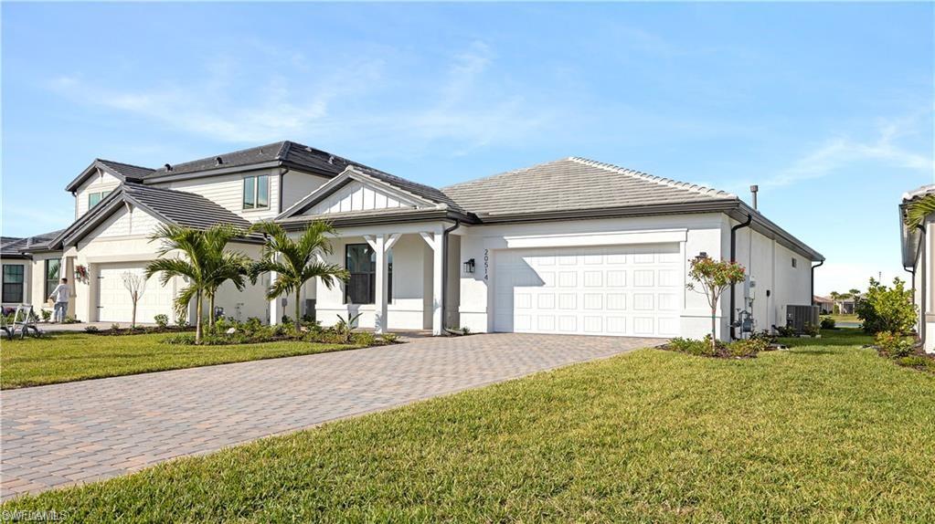 View of front of house with a front yard, decorative driveway, a garage, stucco siding, and a porch