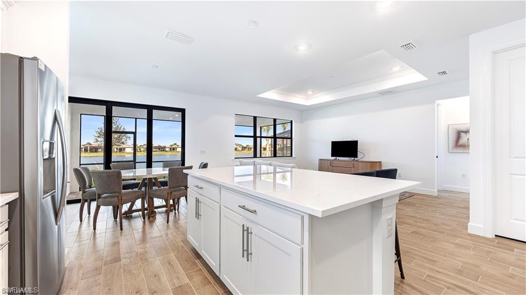 Kitchen featuring stainless steel fridge with ice dispenser, a center island, wood finish floors, a tray ceiling, and crown molding