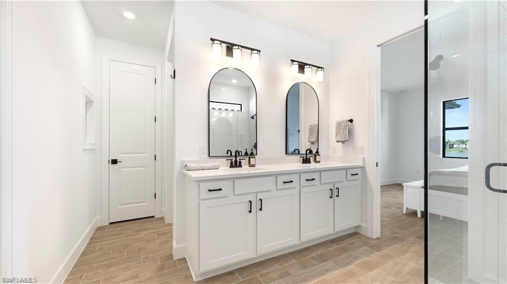 Bathroom featuring double vanity, wood tiled floors, and a shower stall