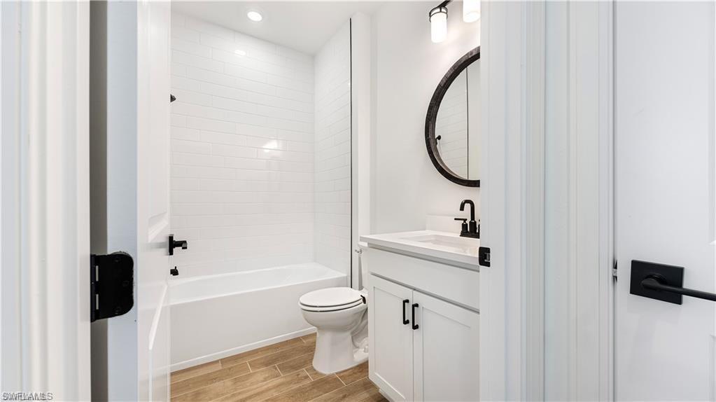 Bathroom with vanity, wood finish floors, and  shower combination